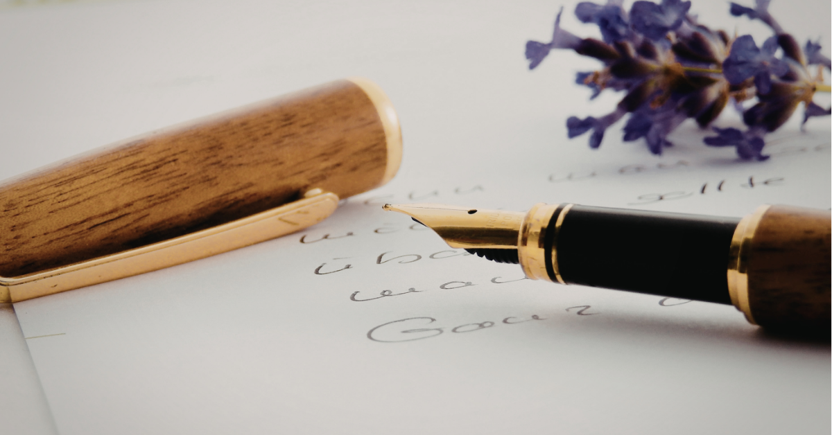 Eine Hand schreibt mit einer Füllfeder einen Brief – Papiergeflüster Club